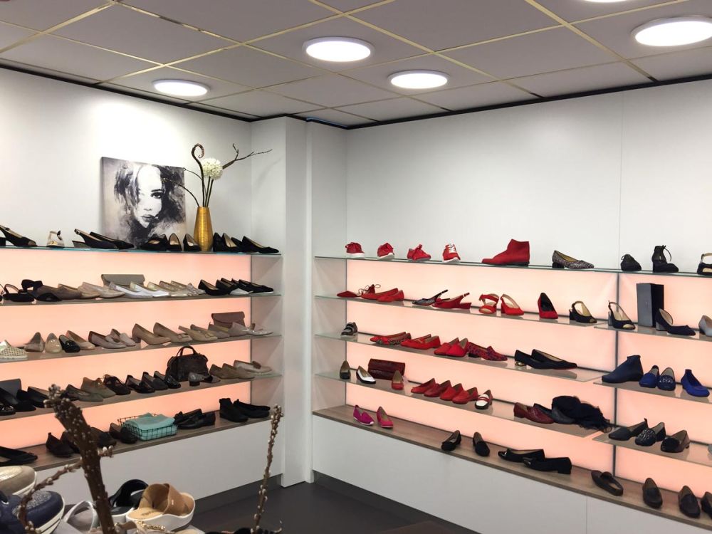 Beleuchtete Schuhregale im exklusiven Ladenausbau von Bäuerlein Objektdesign