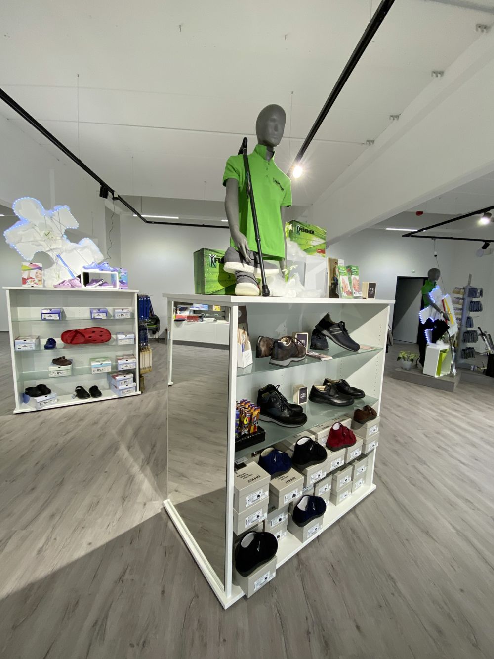 Freistehende Warenträger von Bäuerlein Objektdesign mit stilvoll präsentierten Schuhen – funktional platziert für eine bequeme Anprobe.