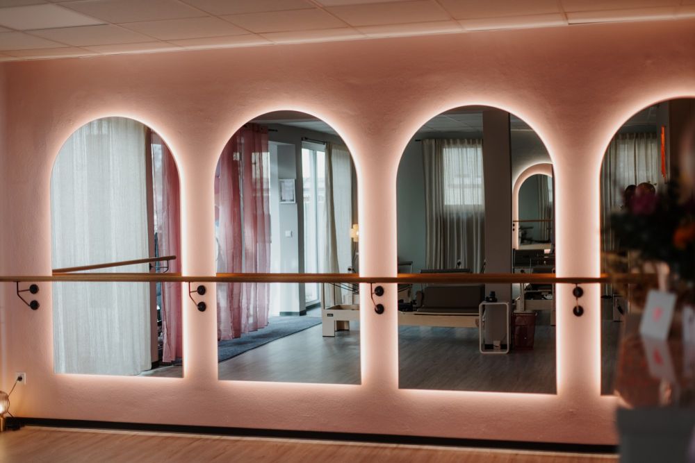 Wandansicht mit abgerundeten, hinterleuchteten Spiegeln und Ballettstange. Gestaltung von Bäuerlein Objektdesign