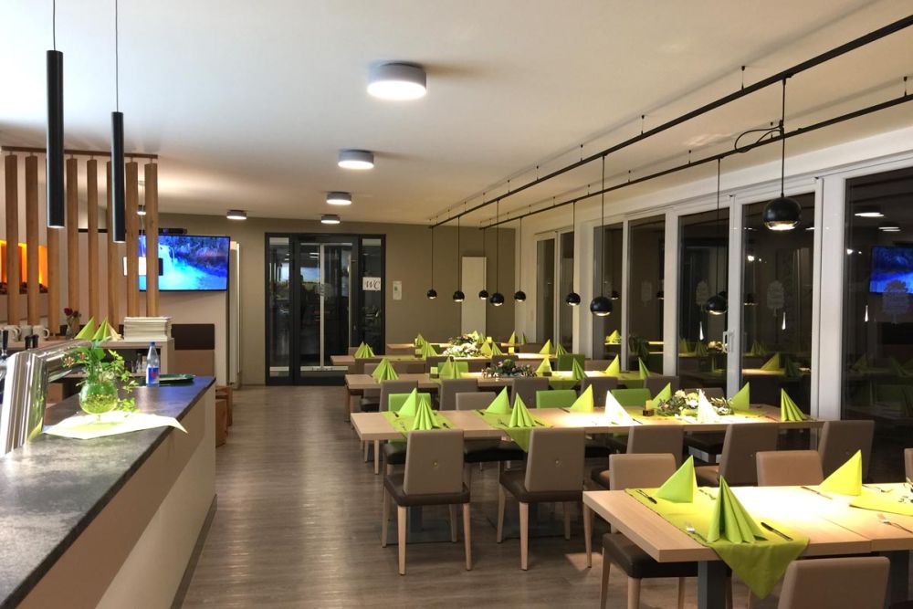 Gastraum mit Tischen entlang der Fensterfront im Landgasthof Grüner Baum Steinfurt, gestaltet von Bäuerlein Objektdesign.