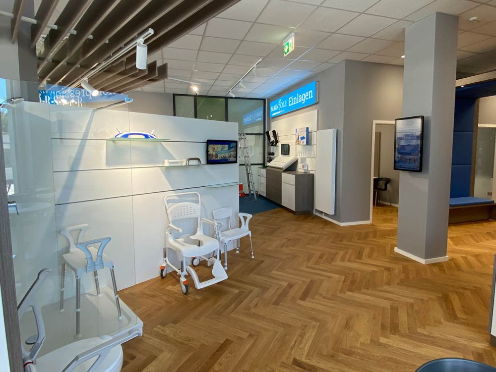 Die individuell gestalteten Elemente bieten funktionale Ablage- und Demonstrationsflächen und fügen sich harmonisch in das Gesamtkonzept des barrierefreien, modern ausgebauten Raums ein.