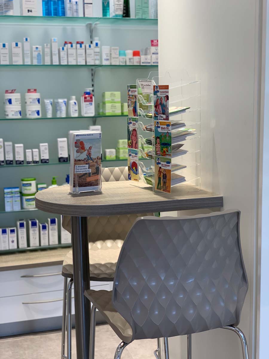 Bild der gemütlichen Warteecke in der SaniPep Apotheke, ausgestattet mit einem kleinen Tisch von Bäuerlein Objektdesign
