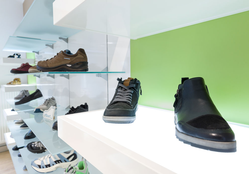 Ein Wandregal mit ästhetisch ansprechend platzierten Schuhen im Ladendesign von Bäuerlein Objektdesign