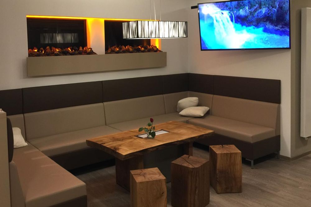 Sitzecke mit einem Flachbildfernseher im Landgasthof Grüner Baum Steinfurt, gestaltet von Bäuerlein Objektdesign.